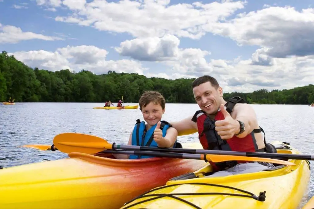 Father and son kayaking together on a lake.