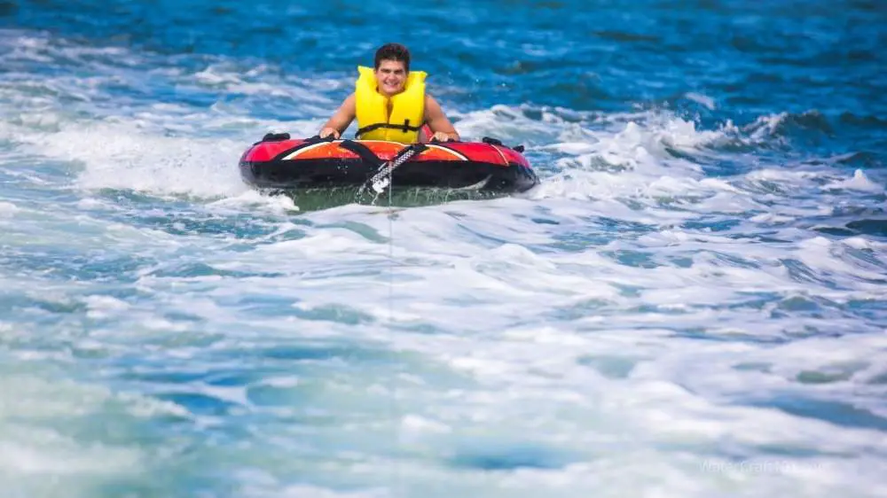 A boy in a tube being pulled on the water.