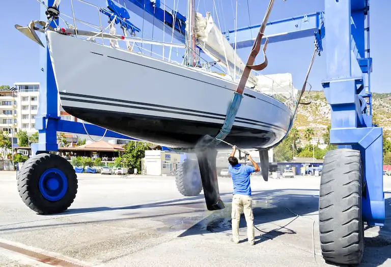 Man washing keel on sailboat: A keel can prevent a sailboat from capsizing when it heels.