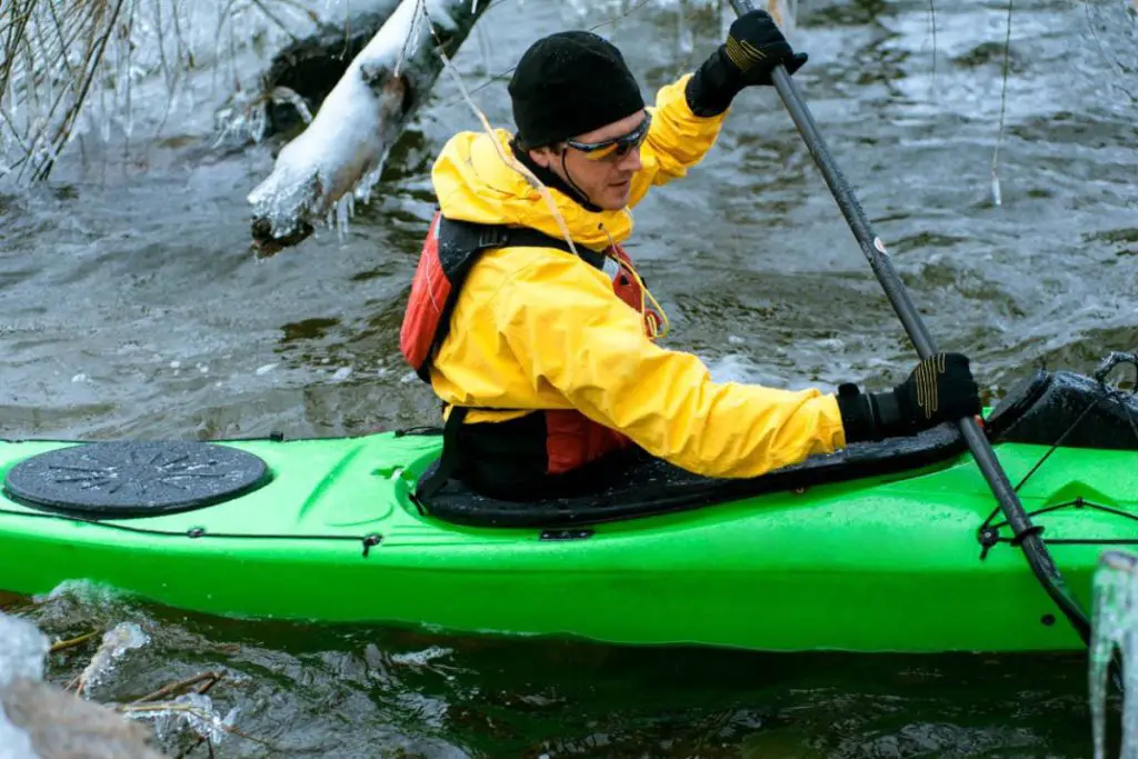 man paddling a kayak in cold, icy conditions